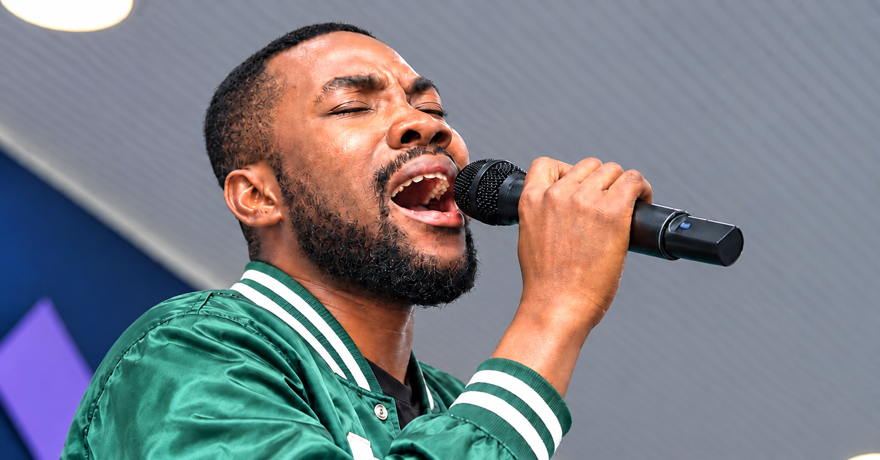 Schadrac Loman en bomber vert, chantant au microphone